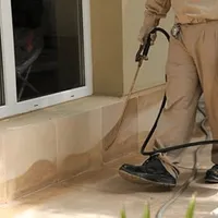 General pest control technician spraying exterior perimeter around a home in Pueblo, CO
