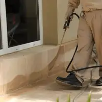 General pest control technician spraying exterior perimeter around a home in Pueblo, CO