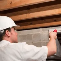 Termite inspection technician checking a basement wall and framing for termite activity in Pueblo, CO