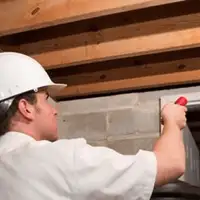 Termite inspection technician checking a basement wall and framing for termite activity in Pueblo, CO